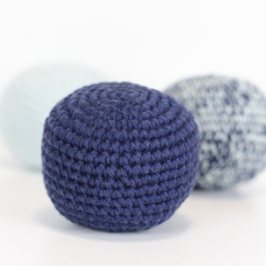 Three crocheted balls, navy blue, merle blue and baby blue. Handmade crochet dog toys from Lana Royals Pet Wear.