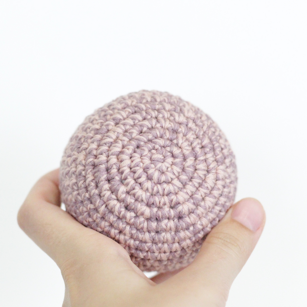Hand holding a pink crocheted ball. Handmade crochet dog toys from Lana Royals Pet Wear.