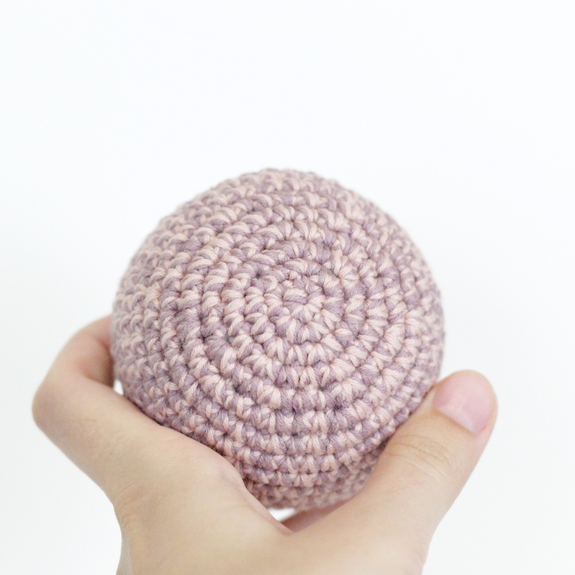 Hand holding a pink crocheted ball. Handmade crochet dog toys from Lana Royals Pet Wear.