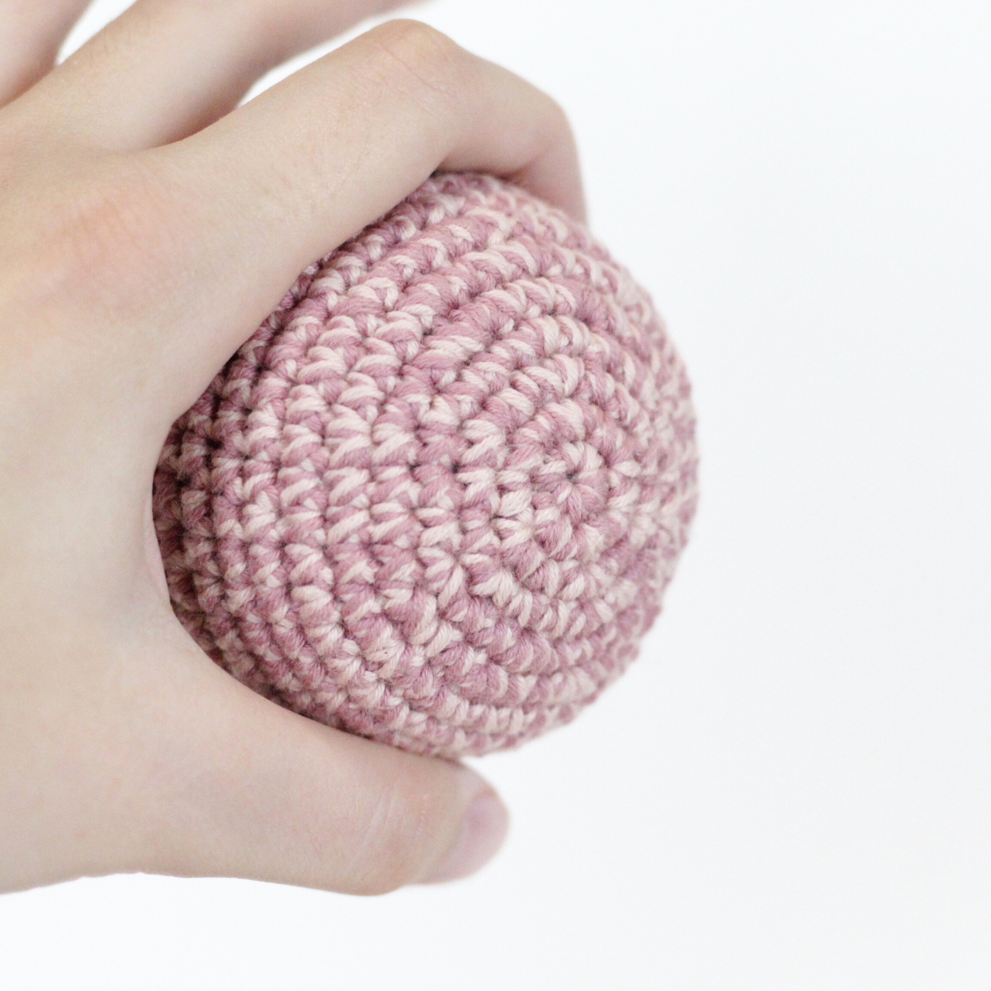 Hand holding a pink crocheted ball. Handmade crochet dog toys from Lana Royals Pet Wear.