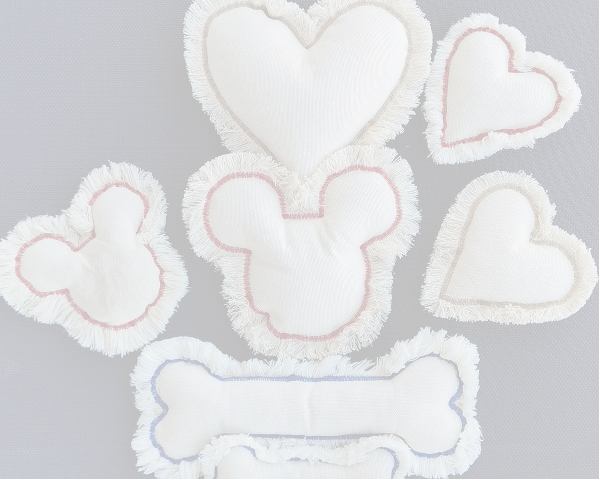 Heart and bone-shaped dog toys from canvas and red stitching on a light gray background
