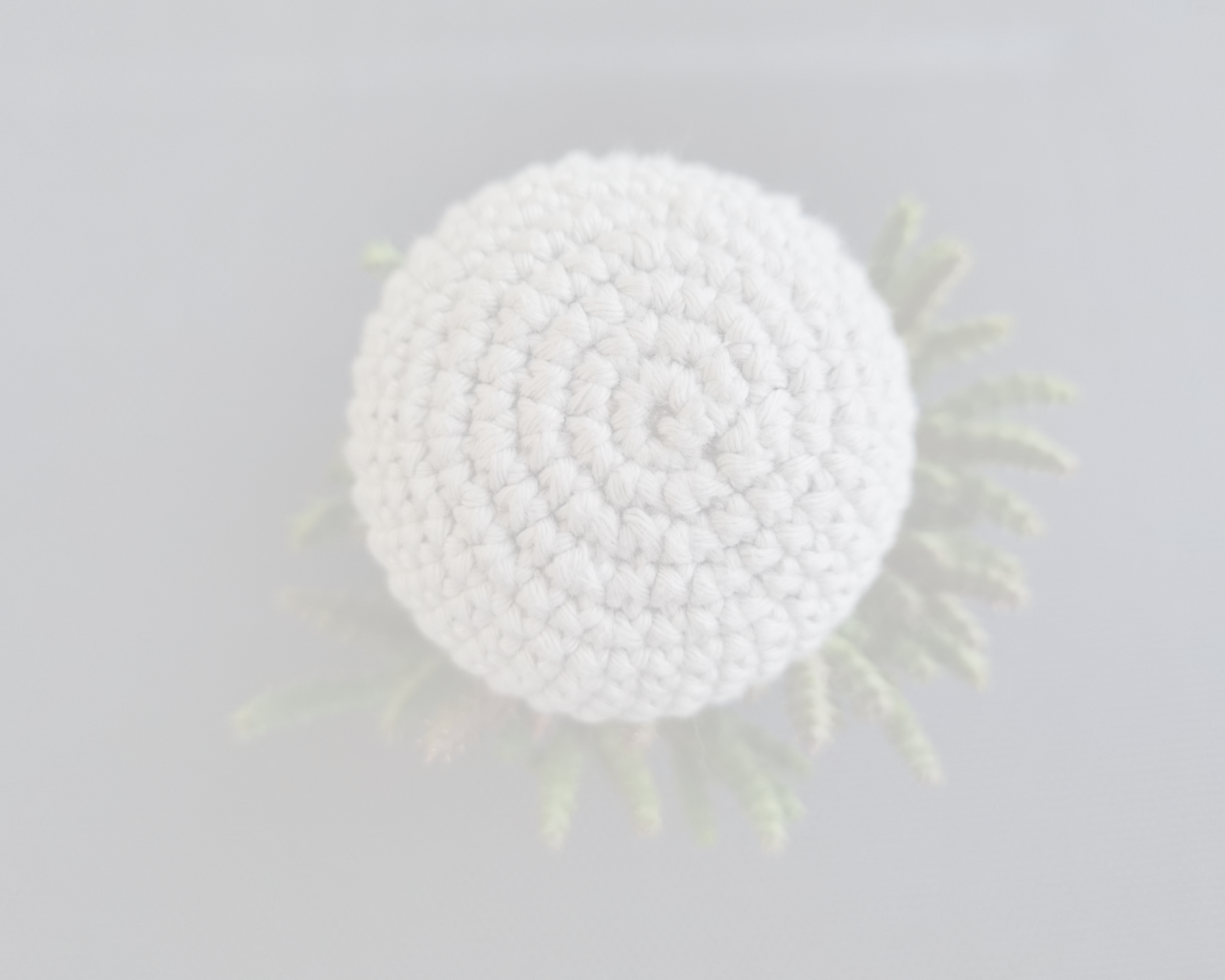 White crocheted ball with a textured surface on a light gray background