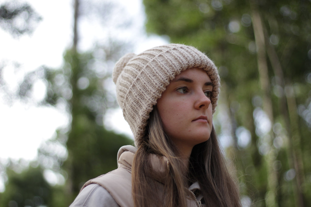 Woman wearing a wool knit beanie in a forest setting. Handmade by Lana Royals Pet Wear Store.