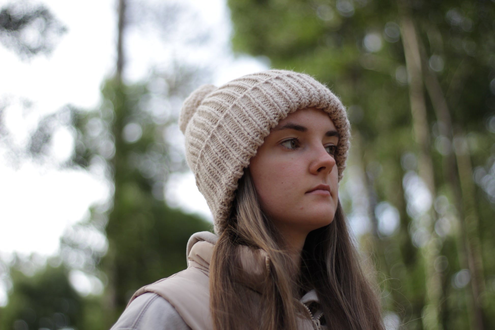 Woman wearing a wool knit beanie in a forest setting. Handmade by Lana Royals Pet Wear Store.
